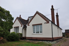 The front of a dormer bungalow that is covered in white external wall insulation.